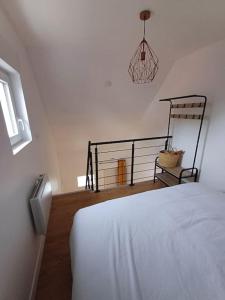 a bedroom with a white bed and a balcony at Au Petit Nid in Bergues