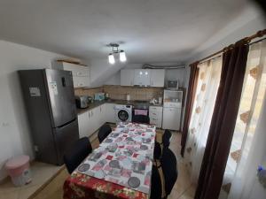 une cuisine avec une longue table avec des chaises et un réfrigérateur dans l'établissement Pensiunea Aly, à Bumbesti Pitic