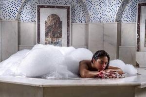 a woman laying in a bubble bath in a tub at Turkishbath spa wellnes in Fethiye