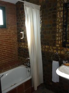 a bathroom with a white shower curtain and a tub and a sink at Rincón del Abade in Encinasola