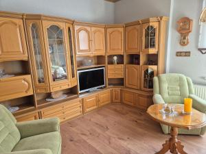 a living room with wooden cabinets and a tv at Ferienwohnung am Hammerberg in Schönheide