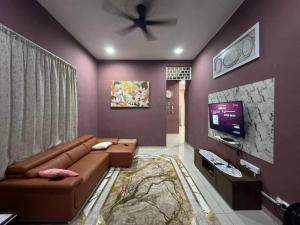 - un salon avec un canapé brun et une télévision dans l'établissement Norelsya Homestay Bemban Melaka, à Bemban