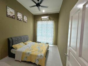 une chambre avec un lit et un ventilateur de plafond dans l'établissement Norelsya Homestay Bemban Melaka, à Bemban