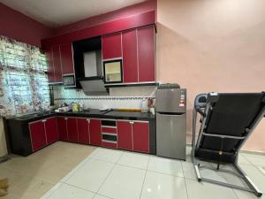 - une cuisine avec des placards rouges et une chaise dans la chambre dans l'établissement Norelsya Homestay Bemban Melaka, à Bemban 5 autres photos