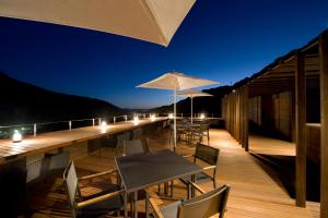 a wooden deck with tables and chairs and an umbrella at Aura Tachibana in Hakone