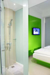 1 dormitorio con pared de acento verde y ducha en POP! Hotel Diponegoro en Surabaya