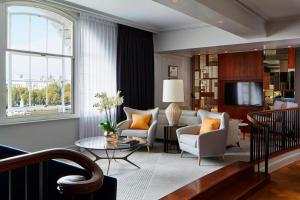 a living room with a couch and chairs and a tv at London Marriott Hotel County Hall in London