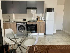 a kitchen with a glass table and white appliances at Cozy nest apartment in Pretoria