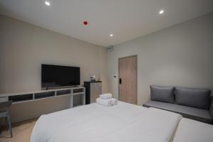 a bedroom with a bed and a tv and a couch at ซิตี้วรรณ ราชบุรี in Ratchaburi
