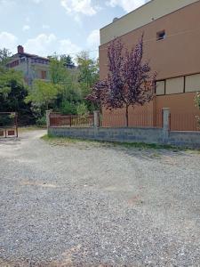 a building with a fence and a tree with purple flowers at Στούντιο κοντά στο Πανεπιστήμιο, περιοχή κόμβος ΤΕΙ in Koíla