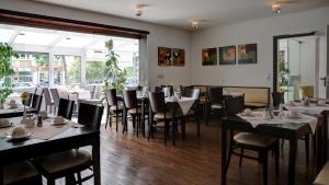 um restaurante com mesas e cadeiras num quarto em Gartenstadt Hotel em Ludwigshafen am Rhein