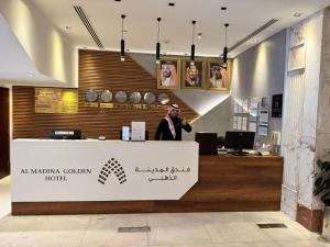 a man standing behind a counter in an office at Al Madina Golden Hotel in Al Madinah