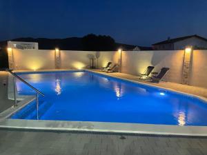 a large swimming pool with blue water at night at Quattro Apartment in Međugorje