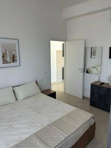 Un dormitorio blanco con una cama grande y una puerta en Appartamento Ginevra, en Nettuno