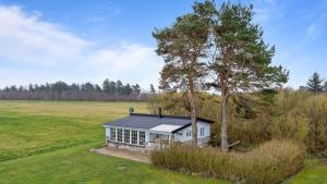ein kleines Haus auf einem Feld mit einem Baum in der Unterkunft Djursland Lystrup Strand Ferieboliger in Allingåbro