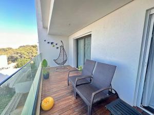 a balcony with two chairs and a table on a deck at Les Jasmins Gammarth, luxueux appartement pour 4 in La Marsa