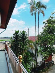 a balcony with palm trees and a white fence at Venn Hostel in Vientiane