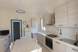 Una cocina con gabinetes blancos y encimera. en Villa Orione 2006, en Fontane Bianche