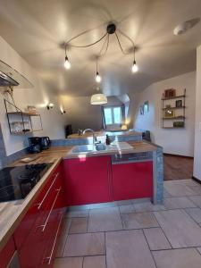 a large kitchen with red cabinets and a sink at Confort entre lac et montagne in Tresserves