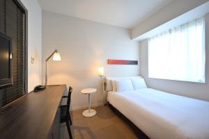 a hotel room with a bed and a desk and a window at Hotel Keihan Tokyo Yotsuya in Tokyo