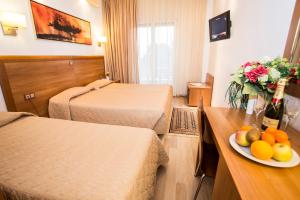 a hotel room with two beds and a plate of fruit on a table at Pefka Hotel in Thessaloniki