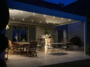 un patio con mesa y sillas bajo toldo en La Ferme Buissonnière, en Bardou