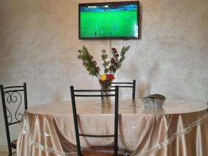 a table with a vase of flowers and a television on a wall at Marwan's apartment 2 in Ifrane