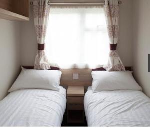 two twin beds in a bedroom with a window at Brand new trio in Porchfield
