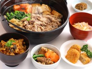 a table with a pot of food and bowls of food at Dormy Inn Tsu in Tsu