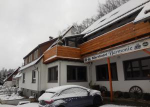 a snow covered house with a car parked in front of it at Biker Hotel Harmonie in Bad Grund +11 photos