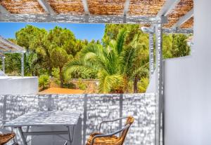 a patio with a table and chairs and palm trees at Coralli Seaside Resort in Livadakia