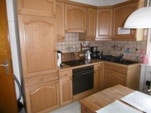 a kitchen with wooden cabinets and a black dishwasher at Fewo Ausblicke in Bodenwerder