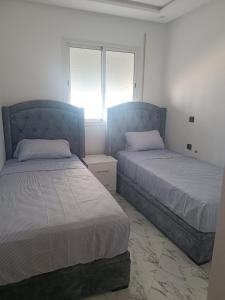 a bedroom with two beds and a window at Appart VIP 2 chambres in Al Hoceïma