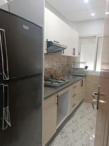 a kitchen with a refrigerator and a stove at Appart VIP 2 chambres in Al Hoceïma