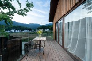 a wooden deck with a table and a chair on it at Wuyuan On The Bound Hotel-婺源水岸边民宿 in Jianlingjue