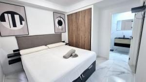 a bedroom with a white bed and a bathroom at Apartamento Lujoso Centro Torrevieja in Torrevieja
