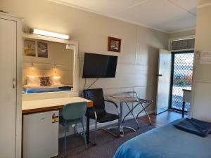a room with a bed and a desk with a computer at Donald Riverside Motel in Donald