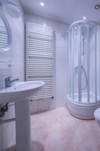 a white bathroom with a sink and a shower at Willa Alpina in Zakopane