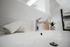 a white bathroom with a sink and a faucet at H30 Apartman in Pécs +28 photos