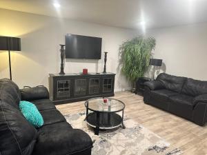 a living room with two couches and a flat screen tv at Exquisite 5 Bedroom Near Airport in Ellenwood