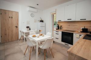 a kitchen with a white table and white chairs at H30 Apartman in Pécs