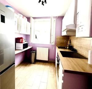 a kitchen with purple walls and a wooden floor at Échappée urbaine in Saint-Jean-des-Vignes