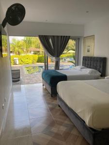 a bedroom with two beds and a large window at Thiago Hotel campestre in Armenia