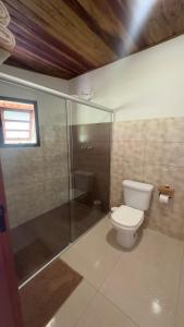 a bathroom with a toilet and a glass shower at Pousada das Flores in Gonçalves