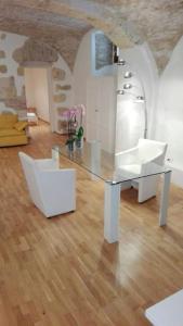 a dining room with a glass table and white chairs at Ibiscus apartment in Cagliari