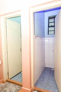 bagno con doccia e piastrelle bianche di 2 bedroom Stylish Apartment, Kisumu a Kisumu