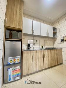 a kitchen with white cabinets and a refrigerator at Scale Apartments in Douala +14 photos