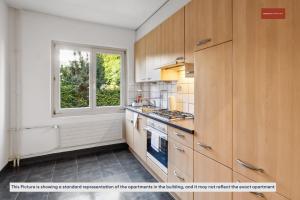 a kitchen with wooden cabinets and a window at Apartment in the heart of Oerlikon in Zürich