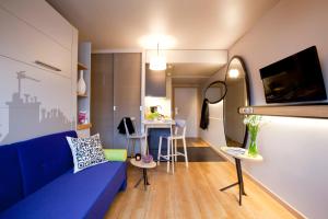 a living room with a blue couch and a kitchen at Aparthotel Adagio access Colombes La Défense in Colombes