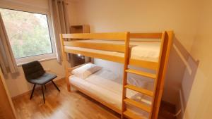 a bedroom with bunk beds with a chair and a window at Ferienwohnung Königsberg in Tieschen
